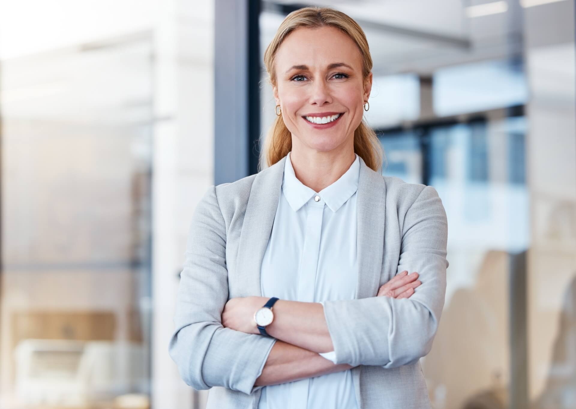 Empowering Businesses Through Leadership Excellence 1 Confident businesswoman representing leadership consulting, standing with arms crossed in a professional office environment.